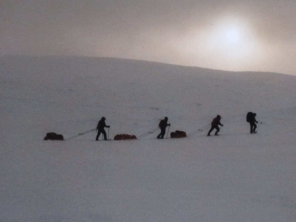 Four people travelling across snowy mountains in Northern Sweden