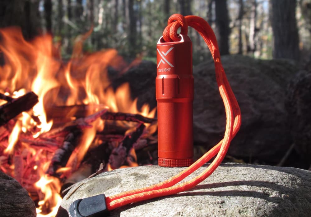 Orange The Exotac TitanLIGHT on a big rock in front of a campfire