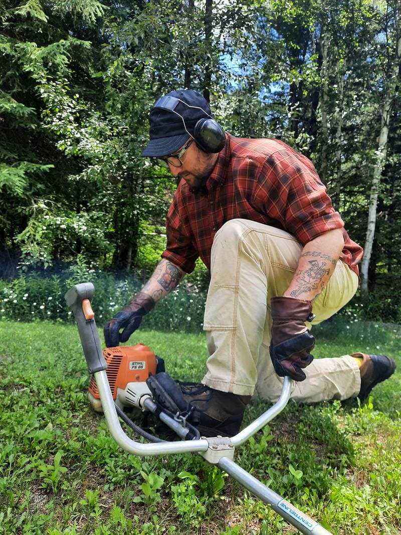 Man weed whacking wearing Hestra Fält Guide Gloves.