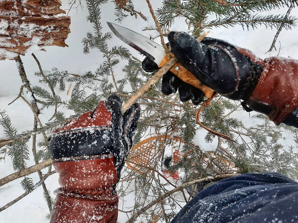 Carving a tree in the snow wearing Hestra Fält Guide Gloves.