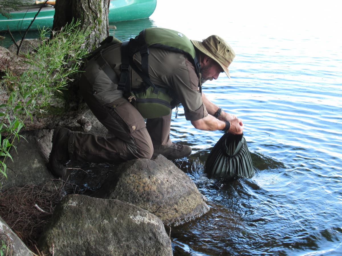 Savotta Water Carrying Bag being filled up by man at lake