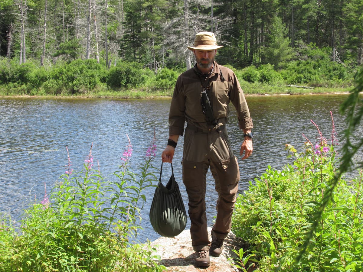 Man carrying water from lake using the Savotta Water Carrying Bag