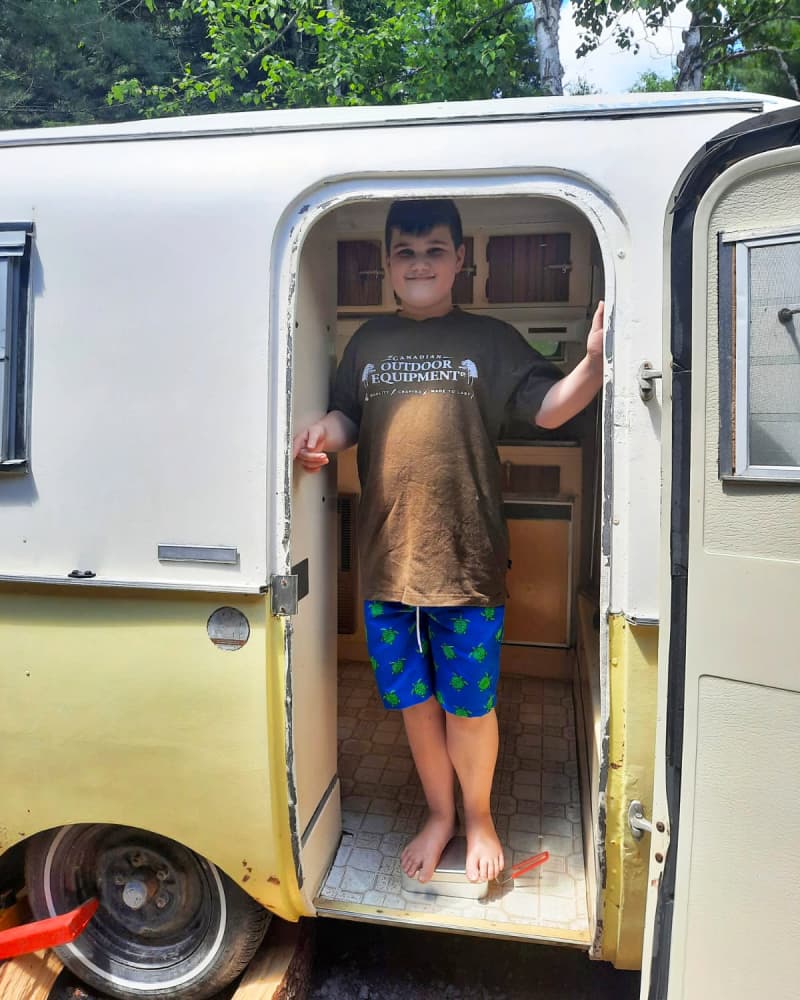 A boy standing in the doorway of a camper.
