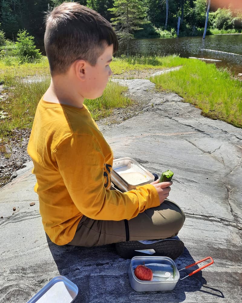 The boy enjoying his lunch outside using his Trangia tins.